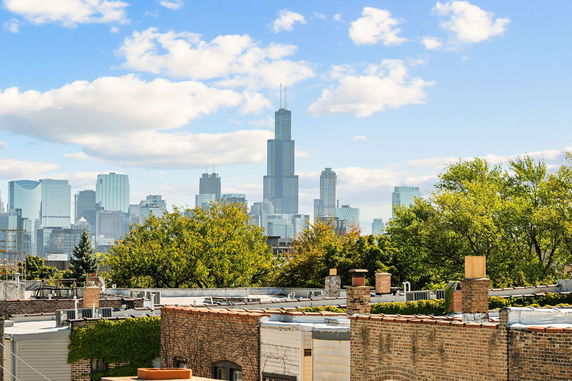 Panoramic view of city skyline with skyscrapers and trees in the foreground.
