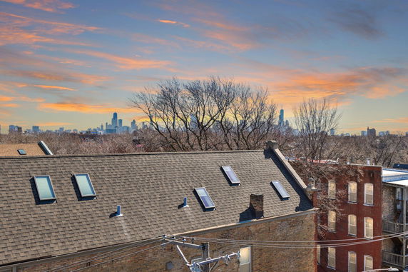 Rooftop with skylights and city skyline in the distance during sunset.