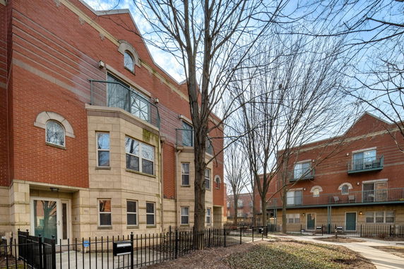 Front view of a multi-story brick building with balconies and arch windows.