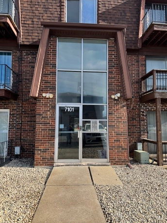 Front view of a brick building entrance with large glass doors and windows.