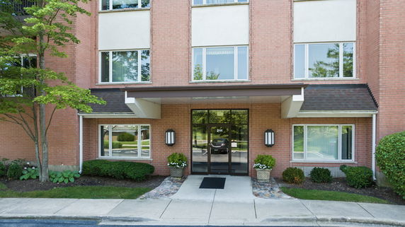 Front view of a brick building entrance with glass doors and windows.