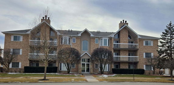 Front view of a multi-story apartment building with balconies and a central entrance.
