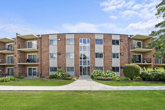 Front view of a multi-story apartment building with brick facade and balconies.
