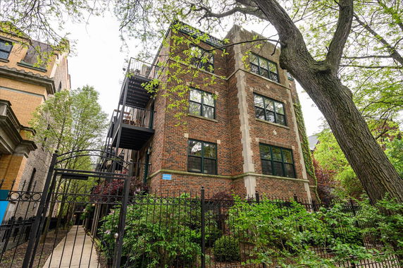 Front view of a brick apartment building with metal fire escape stairs.