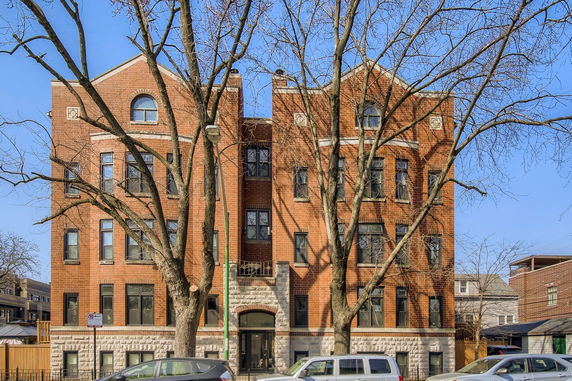 Front view of a multi-story brick building with arched windows and a central entrance.