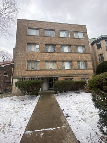 Front view of a multi-story brick building with multiple windows.