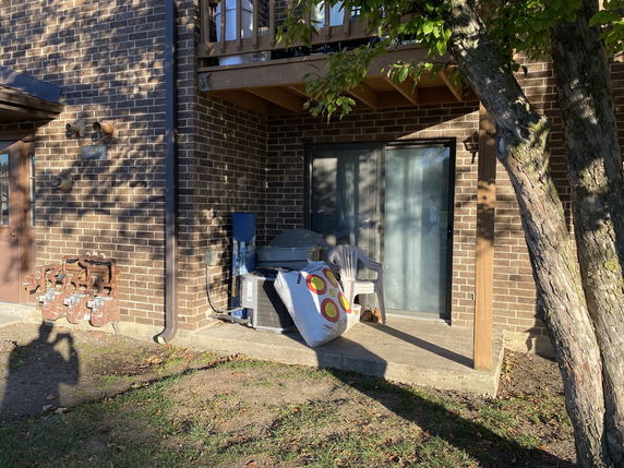 Partial view of a brick house with a patio and sliding glass door.