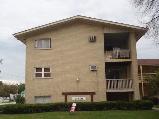 Front view of a multi-story building with beige brick exterior and balconies.