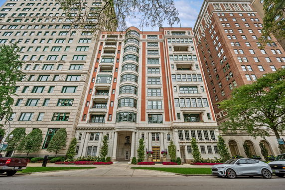 Front view of a multi-story apartment building with a red and white facade and numerous windows.