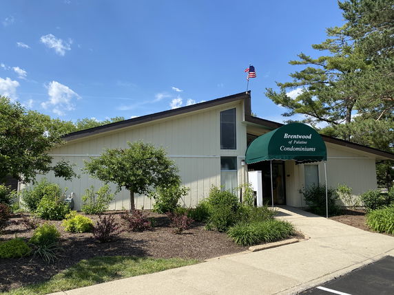 Front view of a building with a sloped roof and an entrance canopy, labeled as Brentwood of Palatine Condominiums.