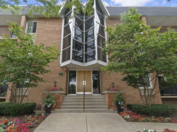 Front view of a building with brick exterior and a geometric window design above the entrance.