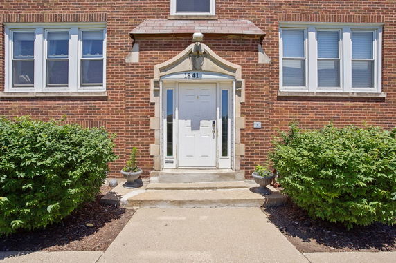 Front view of a brick building with a white door and windows.