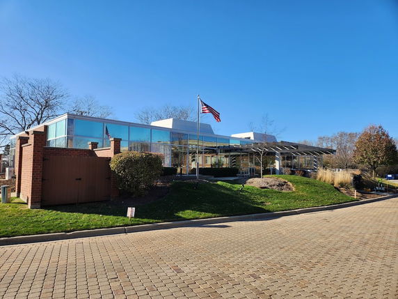 Front view of a modern glass building with a flagpole.
