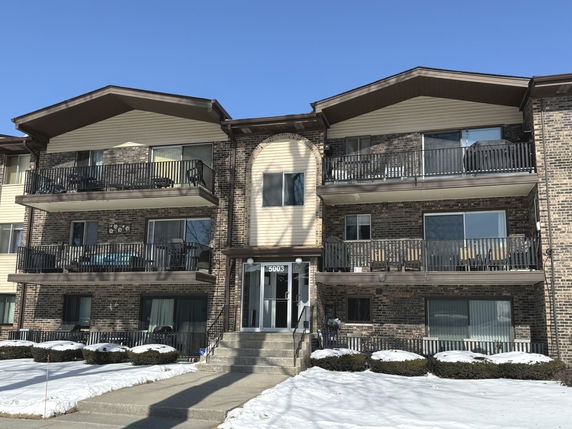 Front view of a multi-story apartment building with balconies.