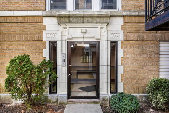 Front view of a building entrance with glass doors and brick walls.