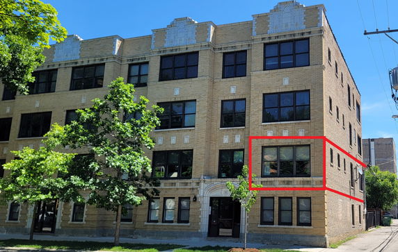 Front view of a multi-story apartment building with brick facade and large windows.