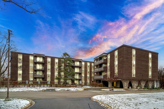 Front view of a multi-story apartment building with balconies and large windows.
