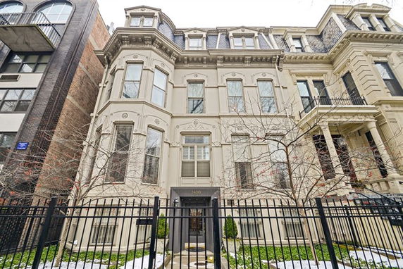 Front view of a multi-story residential building with ornate architectural details and a fenced entrance.