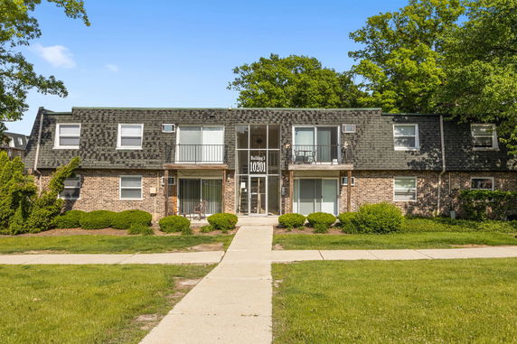 Front view of a two-story brick building with balconies and a central entrance.