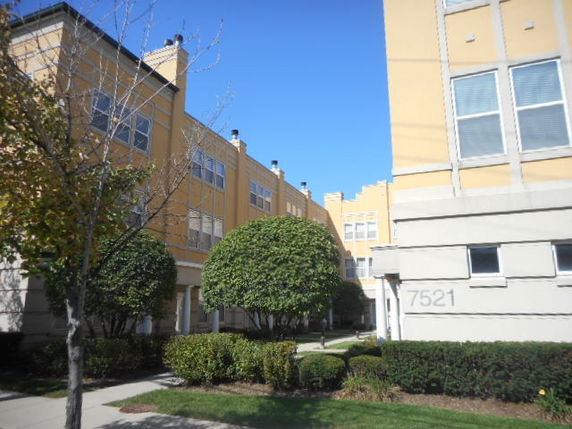 Front view of an apartment complex with yellow exterior and multiple windows.
