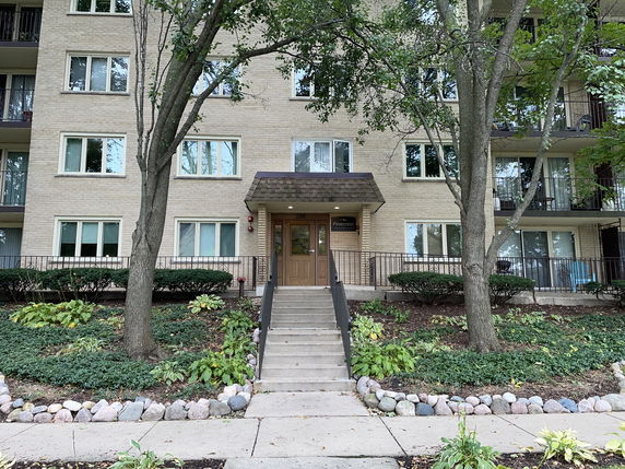 Front view of a multi-story apartment building with a central entrance.