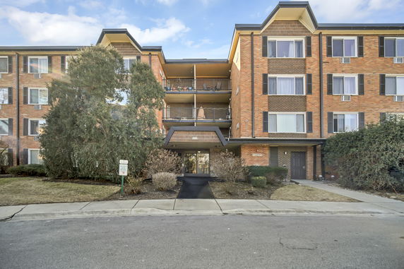 Front view of a multi-story brick building with balconies and a central entrance.