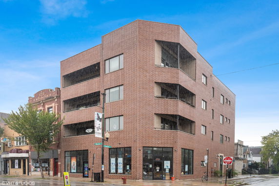 Front view of a four-story brick building with large windows.
