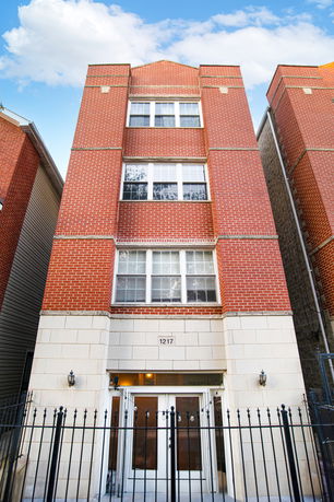 Front view of a multi-story brick building with gated entrance.