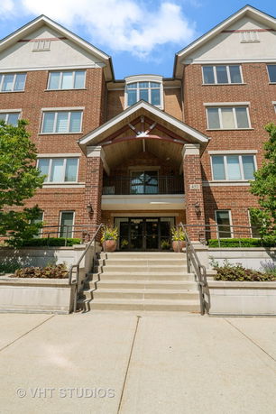 Front view of a multi-story brick building with stairs leading to the entrance.