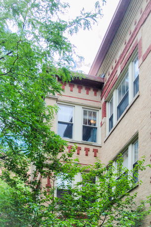 Side view of a multi-story building with brick architecture and decorative window patterns.
