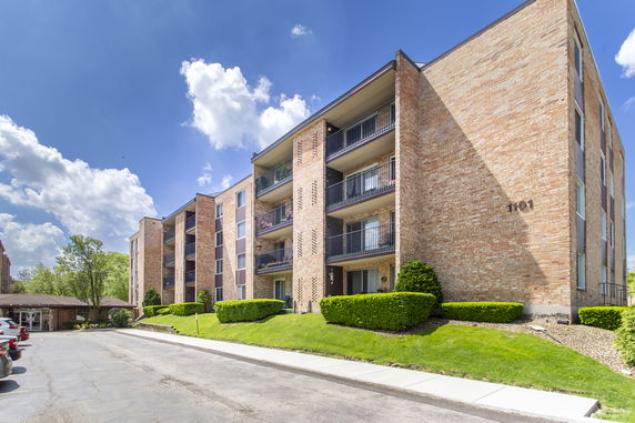 Front view of a multi-story brick apartment building with balconies.
