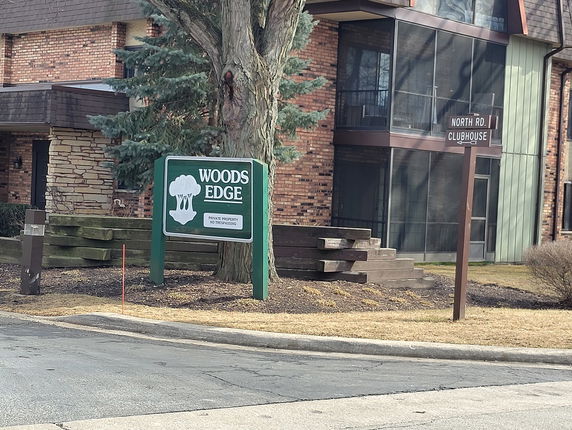 Front view of a brick building with a sign reading 'Woods Edge'.