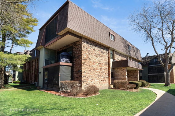 Front view of a multi-story residential building with brick and wood paneling.