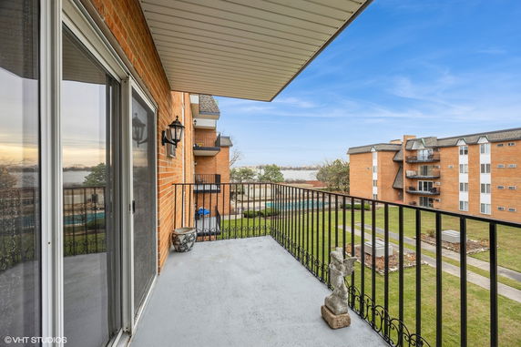 View from a balcony overlooking a residential area with multiple apartment buildings and a body of water in the distance.