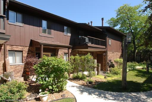 Front view of a two-story house with a balcony and brick exterior.