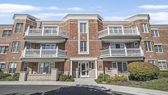Front view of a multi-story brick apartment building with multiple balconies.