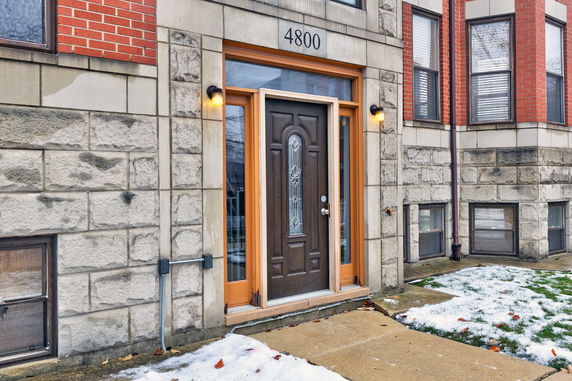 Front view of a building entrance with a wooden door and stone exterior.