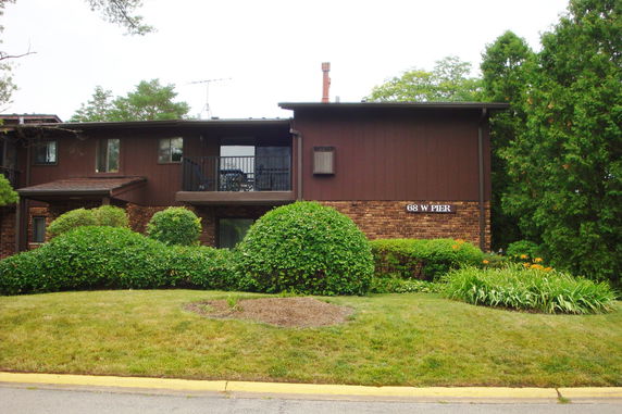 Front view of a two-story house with brown siding and brick accents.
