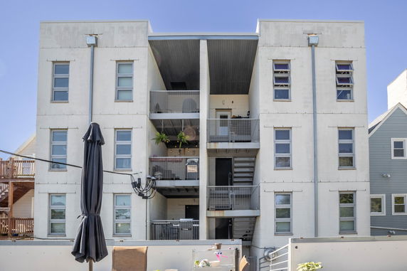Front view of a multi-story apartment building with balconies.