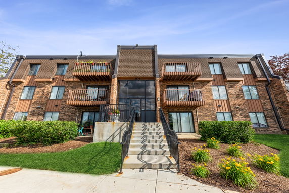 Front view of a multi-story apartment building with balconies and brick facade.