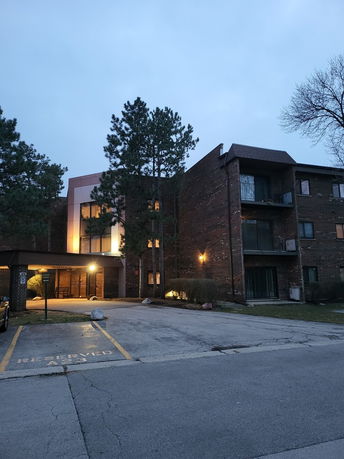 Front view of a multi-story building with a parking area in front.