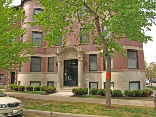 Front view of a multi-story brick building with decorative entrance.