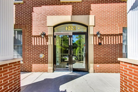 Front view of a building entrance with brick facade and glass doors.