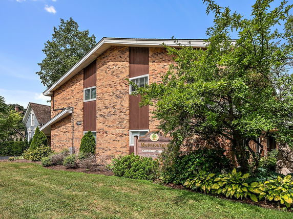 Front view of a brick condominium building with a pitched roof.