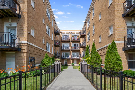 Front view of a multi-story brick apartment building with balconies.