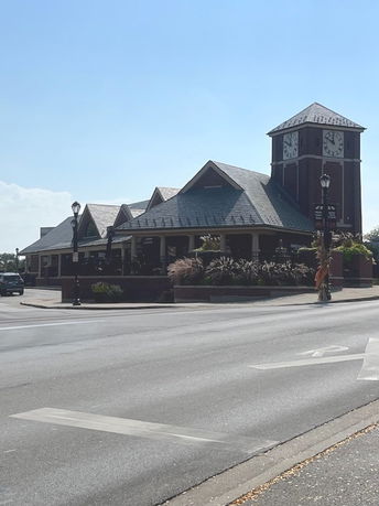 Front view of a building with a clock tower and multiple gabled roofs.