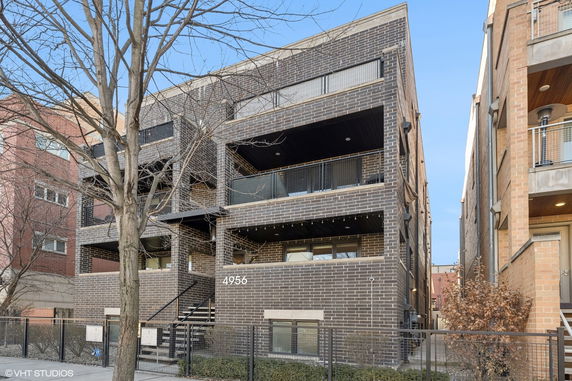 Front view of a multi-story brick apartment building with balconies and stairs.