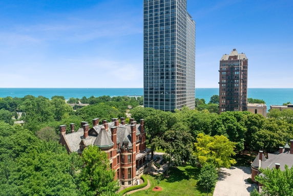 Panoramic view of buildings and surrounding greenery with a view of the sea in the background.