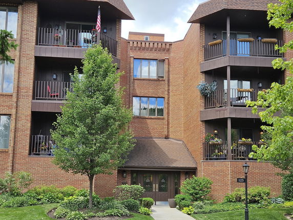 Front view of a multi-story brick apartment building with balconies.