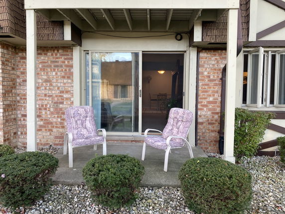 Front view of a house with a brick exterior and patio chairs.